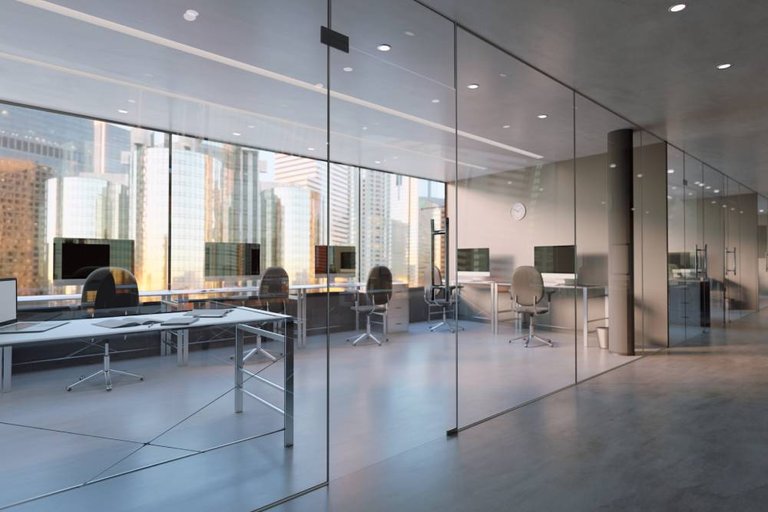 A contemporary office with glass partitions and shared desk areas